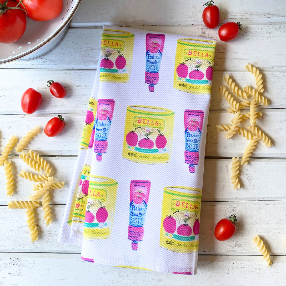 tea towel featuring amy mccoys hand drawn tomato sauce and tomato paste with pasta and fresh tomatoes scattered around on a white wooden background