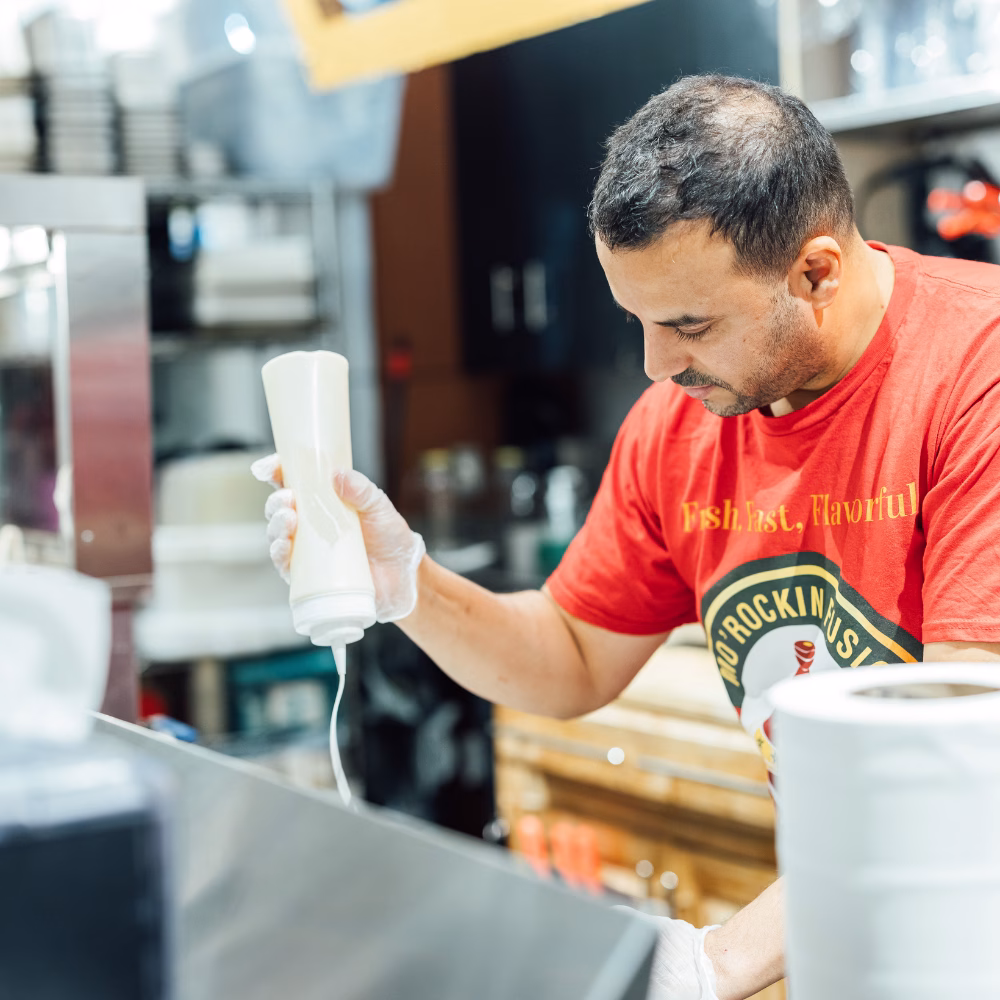 Morad Morockin Fusion Sauce Morad Bouzidi owner of Morockin Fusion finishing off Moroccan bowl with garlic sauce