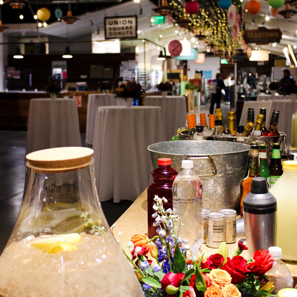 Cocktail party with high tops floral decor and bar setup with beverages in Boston Public Market